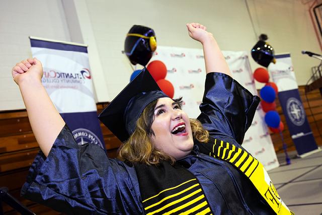 Student in cap and gown with arms raised in celebration
